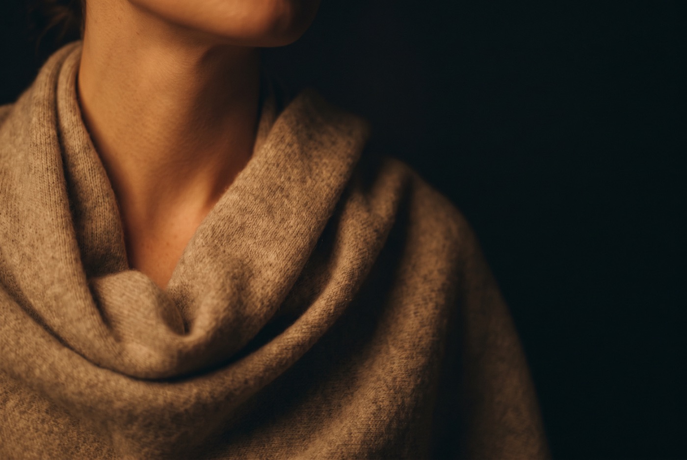 A softly draped wool scarf against a warmly lit neck and shoulder